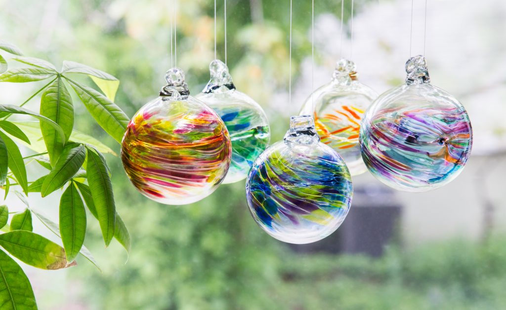 5 hand blown glass birthday ornaments from Kitras Art Glass hang in a window