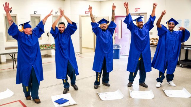5 men in blue graduation cpas & gowns are seen celebrating having graduated from Defy Ventures' entrepreneurship training