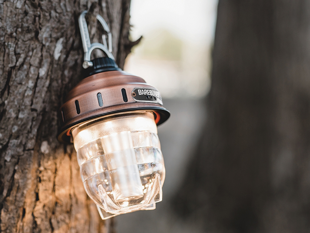 A beacon lantern from Barebones Living hangs on a tree in the woods