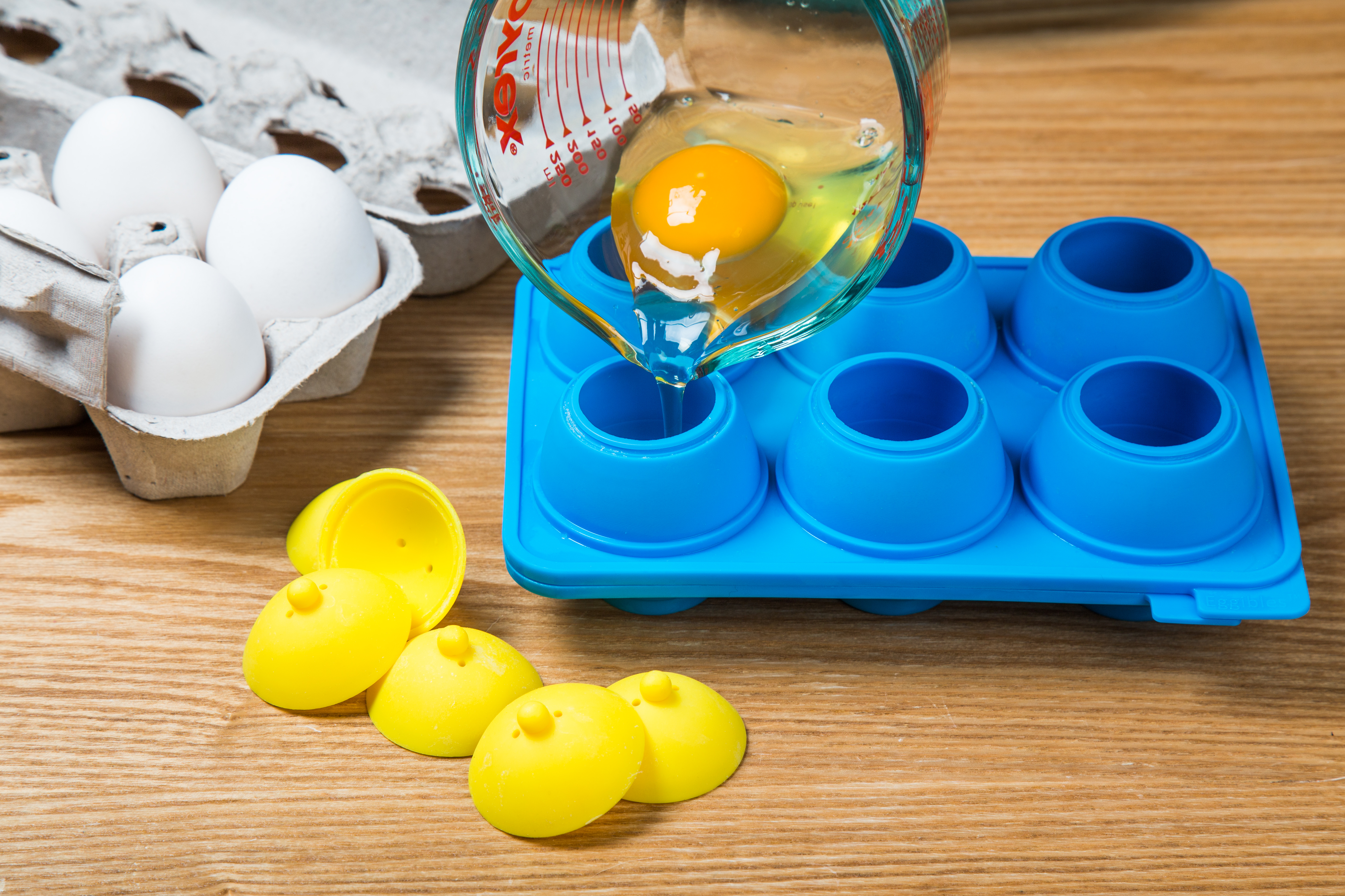 A measuring cup is used to pour a faw egg into  silicone egg mold