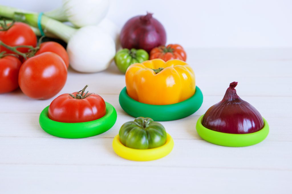 Fresh cut tomatoes, peppers & onions sit wrapped in Food Huggers silicone food savers
