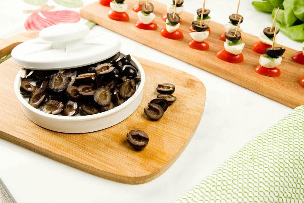 A pile of olives is seen sitting sliced in Rapid Slicer, ready to make caprese skewers