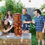 Four people playing Tumbling Timbers on top of a table