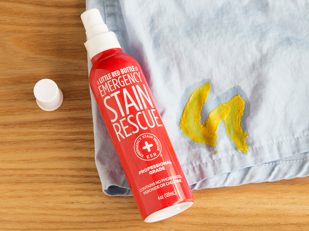 The hate Stain's co's little red bottle of emergency stain remove sits next to a shirt stained with mustard