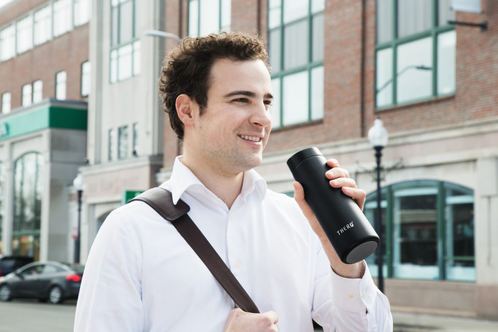 A man is seen walking and drinking from his THERO temperature-controlled travel mug