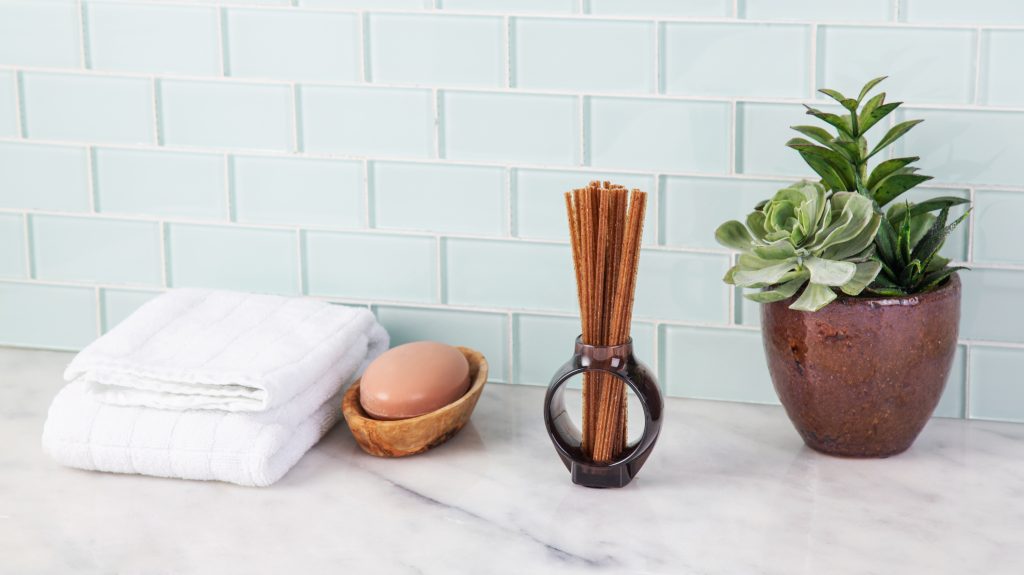 An odor-neutralizing diffuser from Alo sits on a bathroom counter next to soap and towels