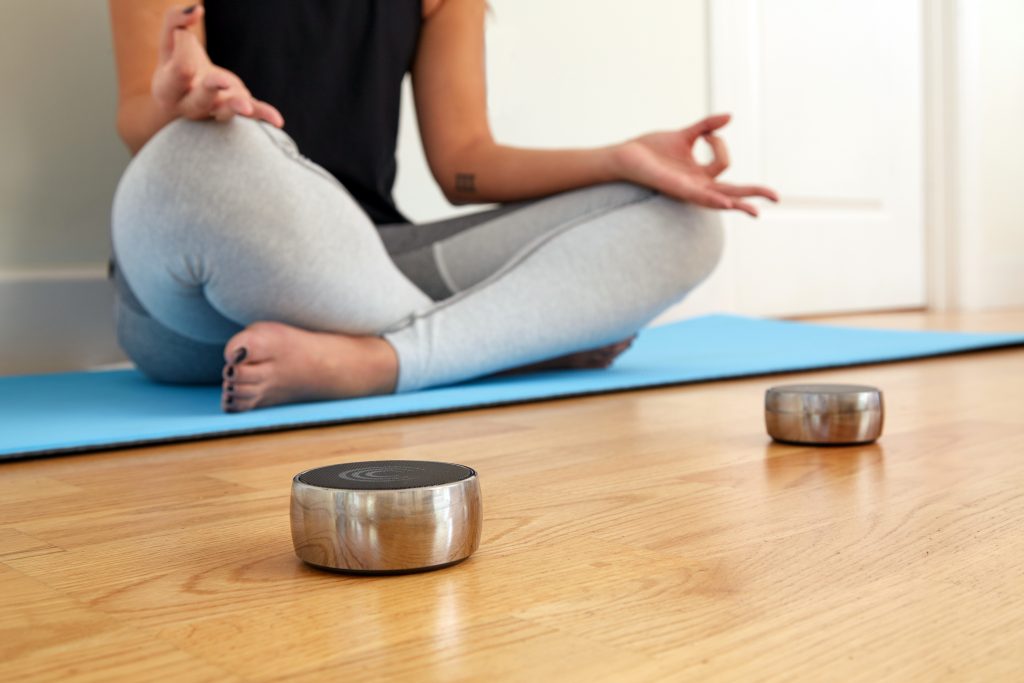 A woman is seen meditating using solu N.O.W's mindfulness tone therapy system