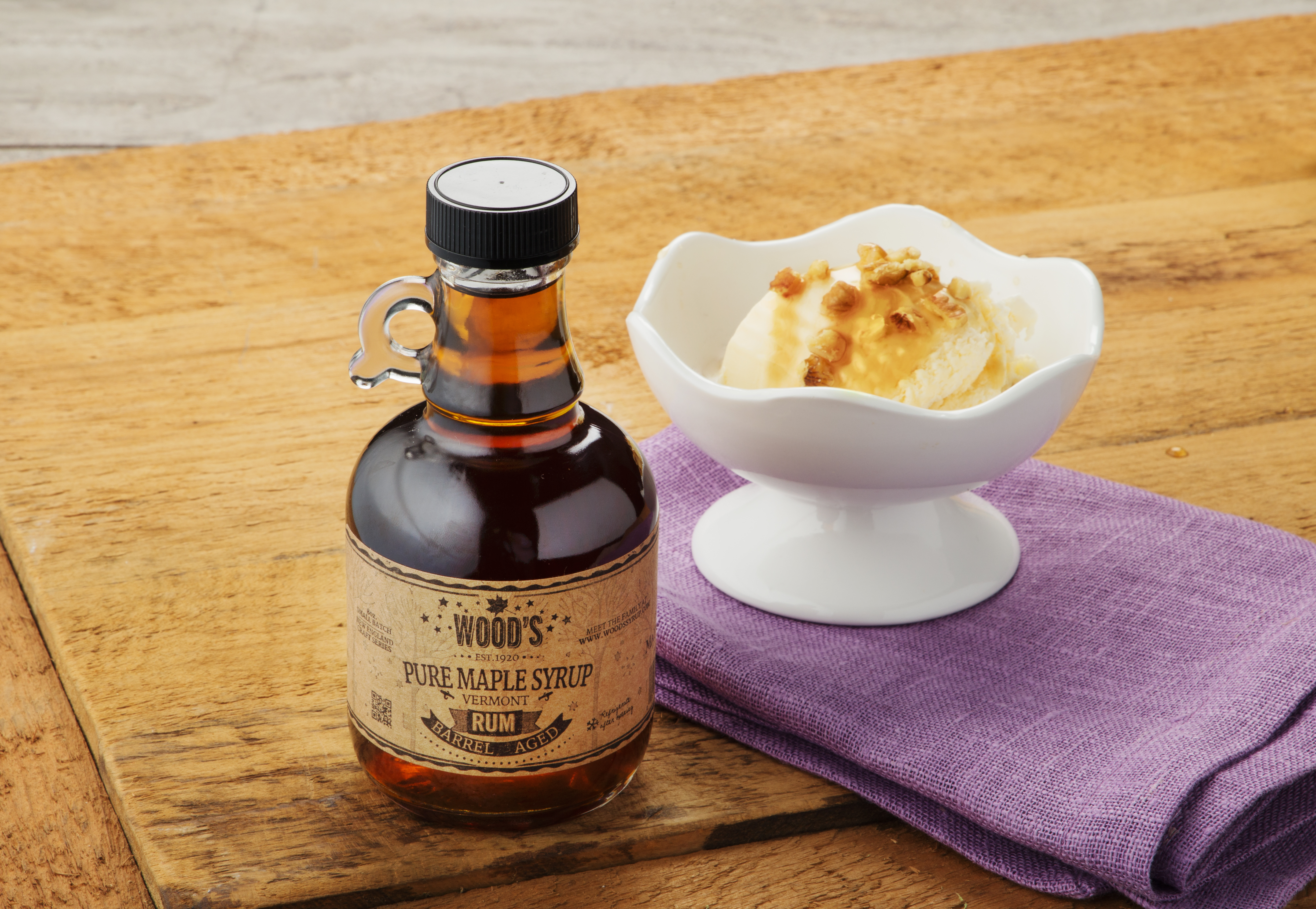 A bottle of Rum-infused Wood's maple syrup sits next to a bowl of ice cream
