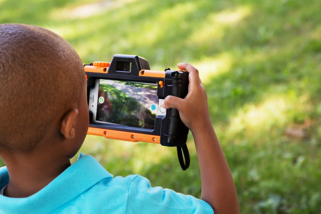 A young boy is seen taking photos with a Pixplay smartphone-enabled camera