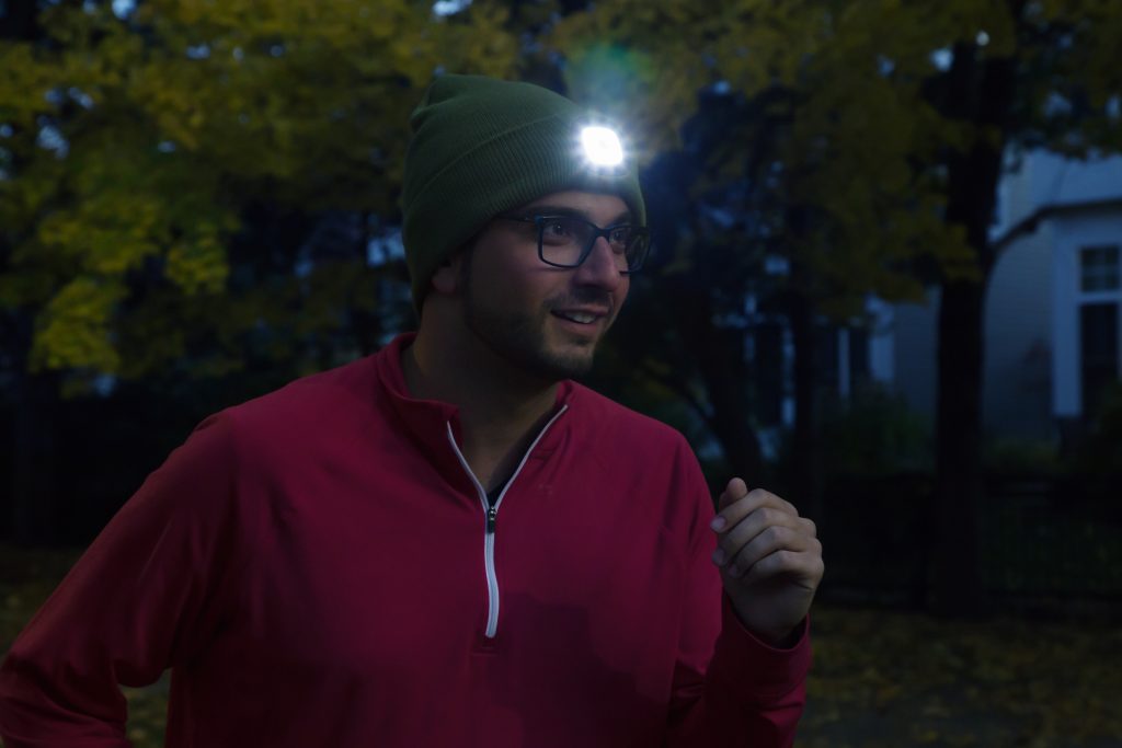 A man running at night wearing a Night Scout lighted beanie
