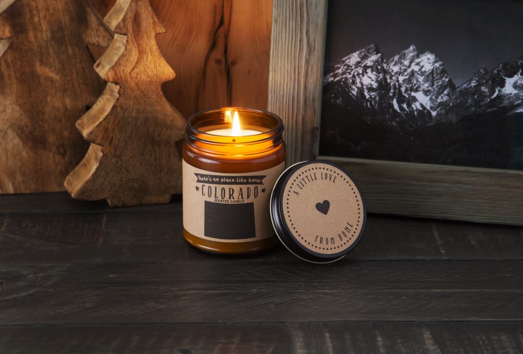 A Colorado state scented candle form no Place Like Home Candles burns on a mantle
