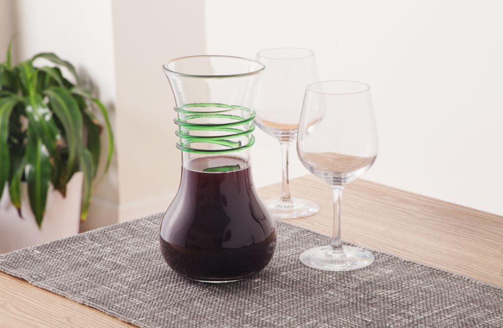 Red wine aerates in a Blenko Glass Company wine carafe accented with green glass spirals