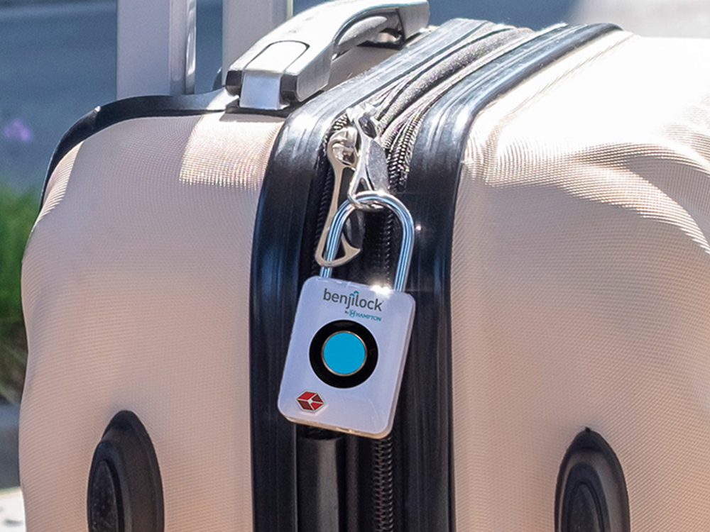 A TSA-approved fingerprint travel lock from Benjilock is seem clipped to a suitecase