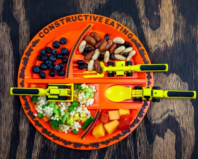 Blueberries, beans, veggie couscous and pineapple are seen on an orange Constructive Eating construction plate set