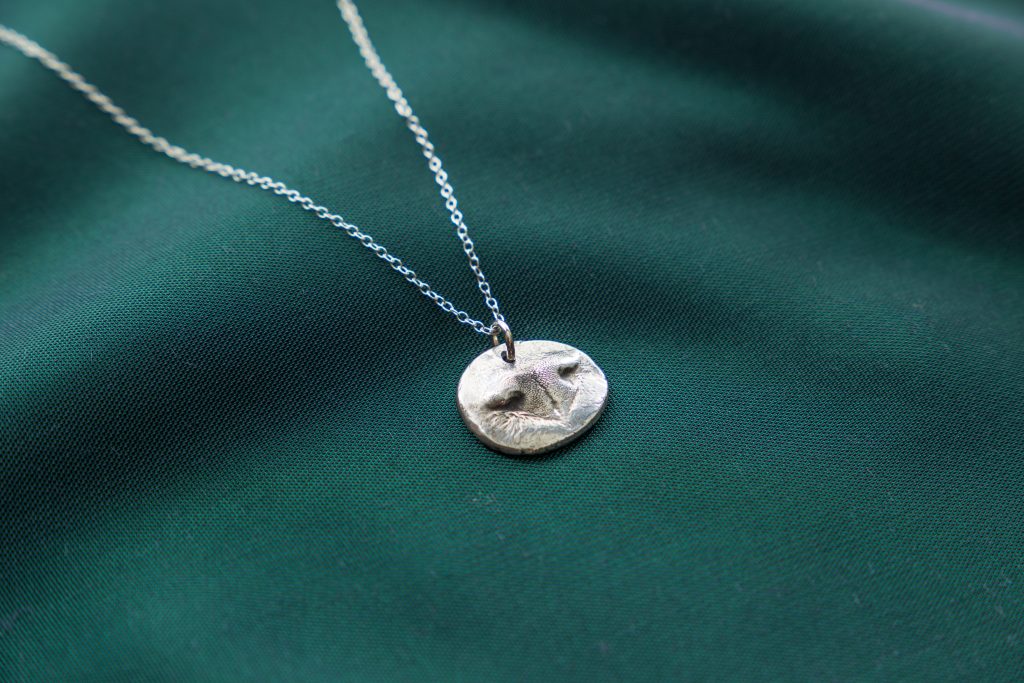 An impression of a pet's nose can be seen captured in a metal pendant necklace from Precious Metal Prints