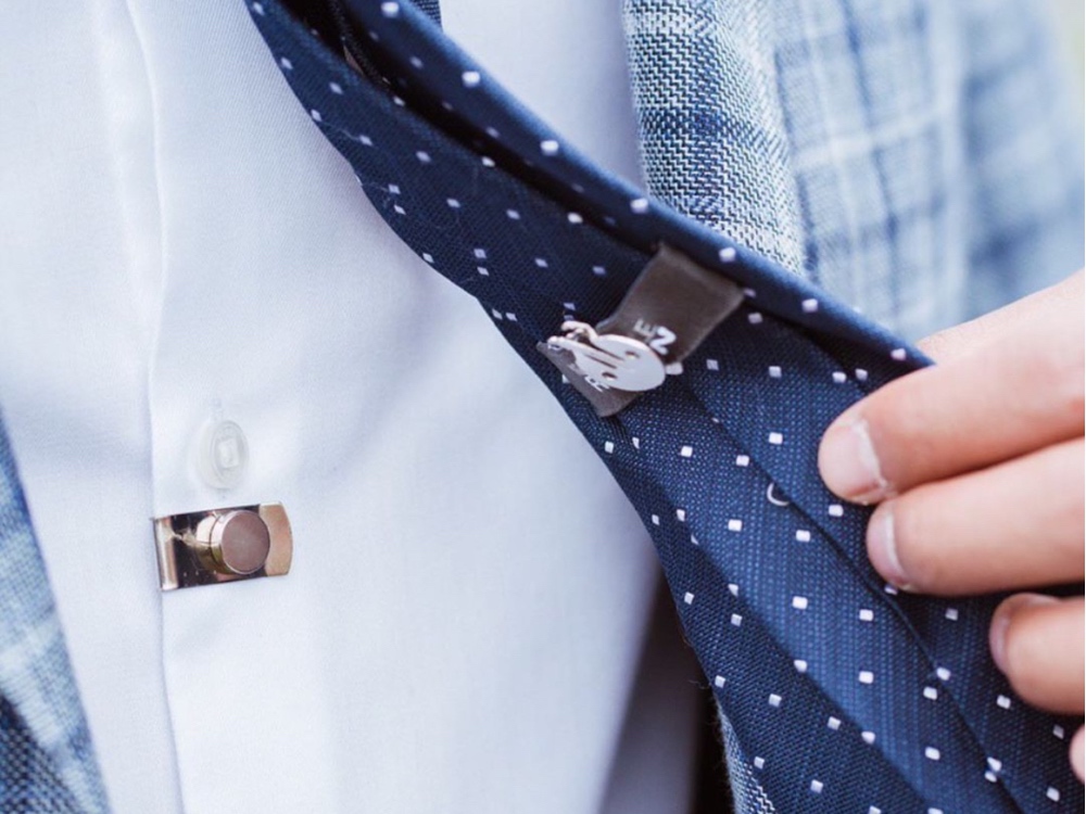Close up of a man's navy polka dot tie securing to his shirt with a CLIP OFF magnetic tie stay