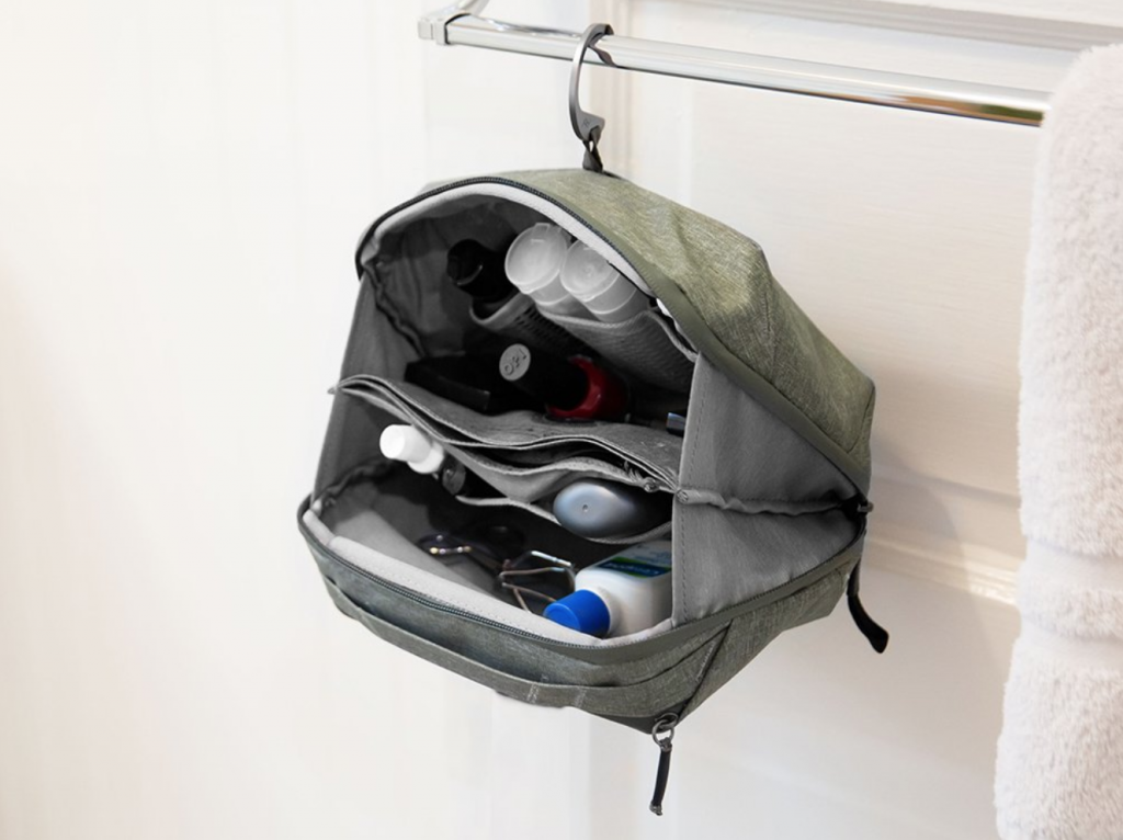 A grey hanging Dopp kit from Peak Design is seen hanging from a towel rack