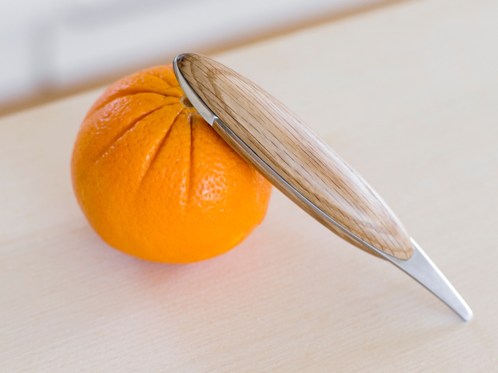 Spring Copenhagen's wooden minimalistic orange peeler rests on an orange