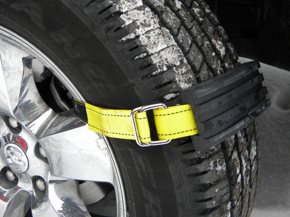 Neon yellow tire traction straps from TRAC-GRABBER are seen strapped to an icy tire