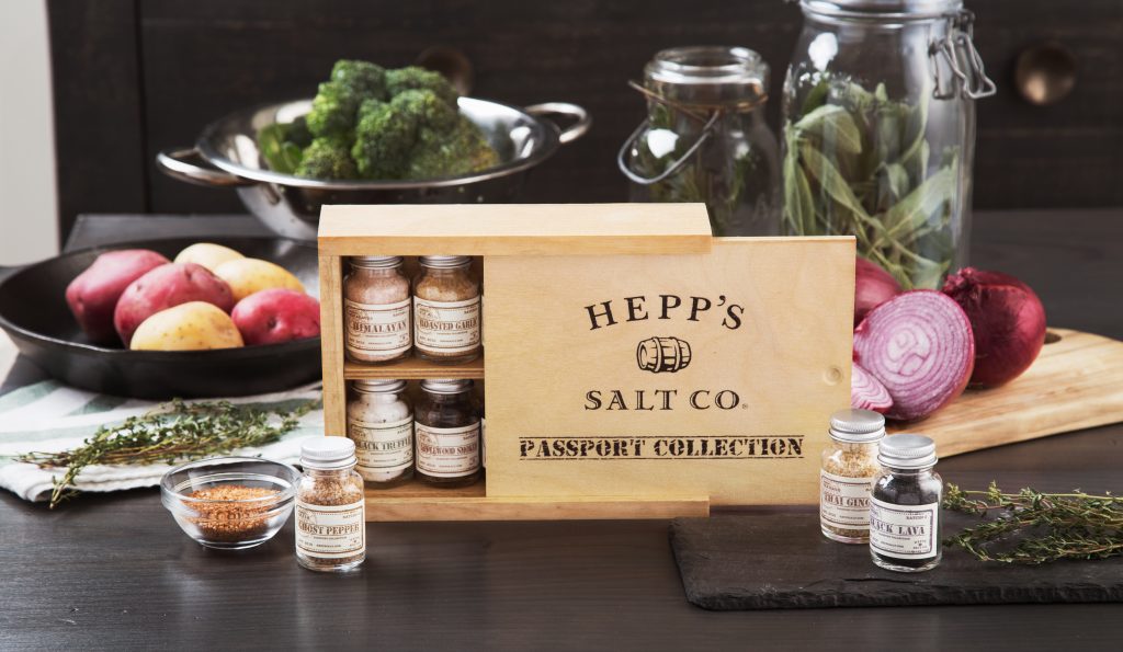 Surrounded by fresh cooking ingredients is a gift box of Hepp Salt Co.'s Passport collection of finishing salts